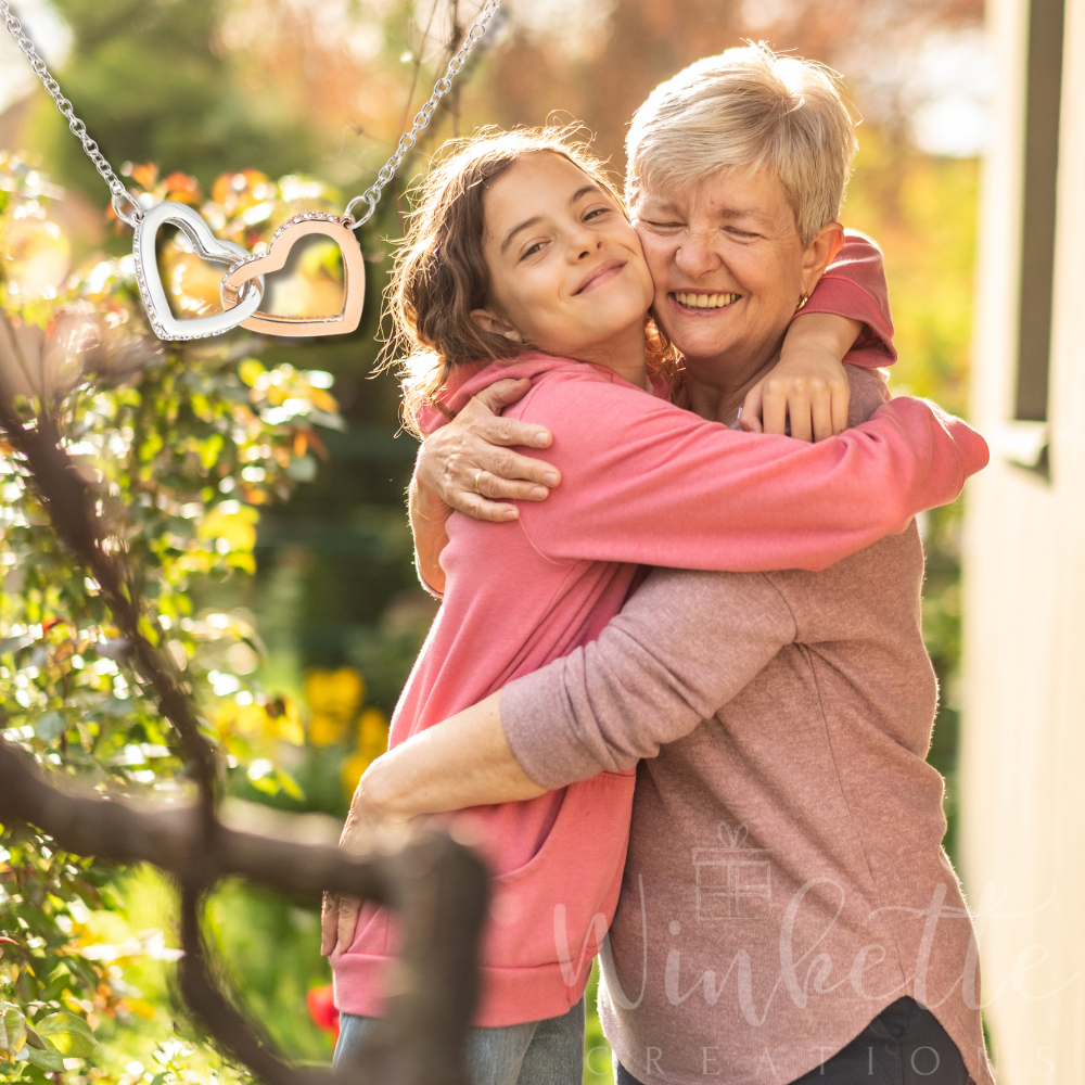 grandma and granddaughter hugging outdoors with a blurred background