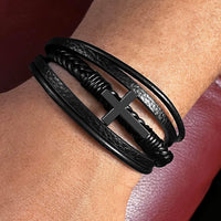 Thumbnail for Close-up of black leather cross bracelet for son with stainless steel cross centerpiece.