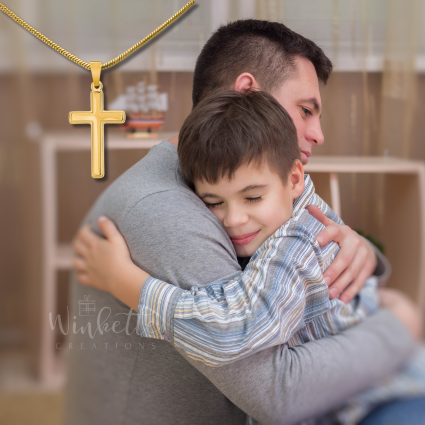 Dad hugging his son with a gold cross necklace in the foreground