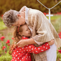 Thumbnail for Grandmother embracing her granddaughter in a field with a cross necklace in the foreground.