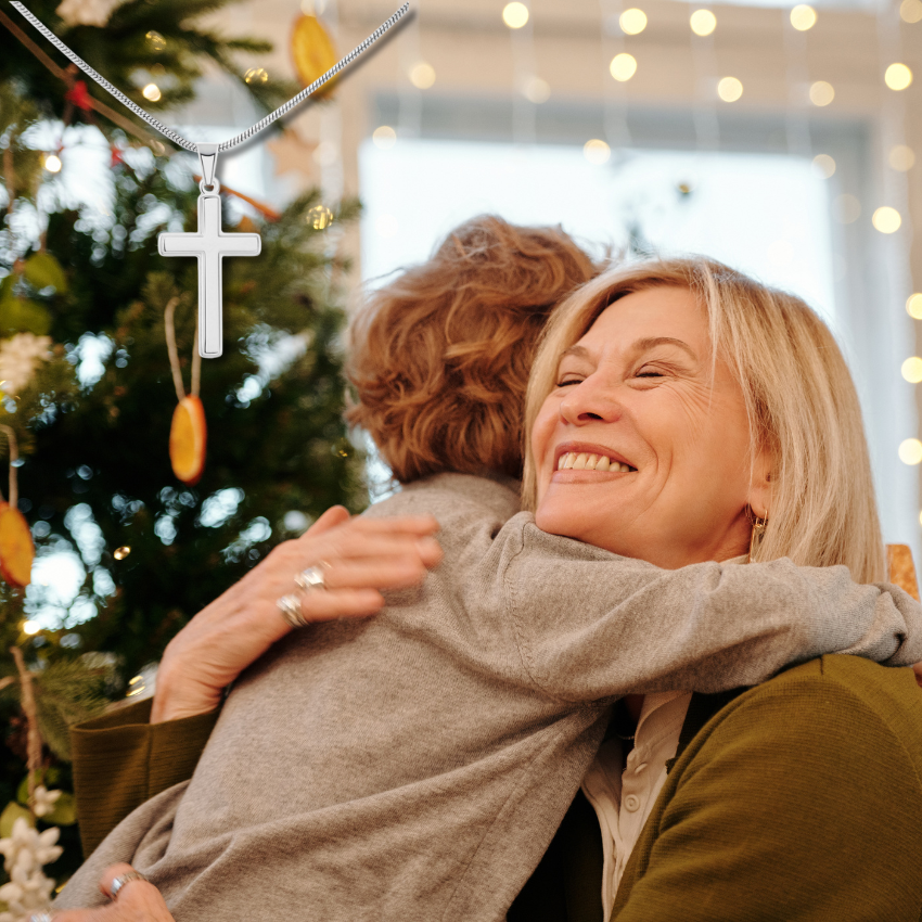Grandson and Grandma hugging in front of a decorated Christmas tree with lights in the background.