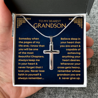 Thumbnail for A silver cross pendant necklace displayed inside a gift box with a navy blue message card addressed 'TO MY DEAREST GRANDSON,' held in a hand.