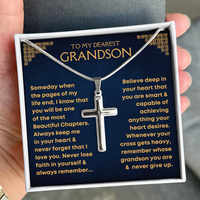 Thumbnail for A silver cross pendant necklace presented in a gift box with a dark blue message card addressed to a grandson, held in a hand.