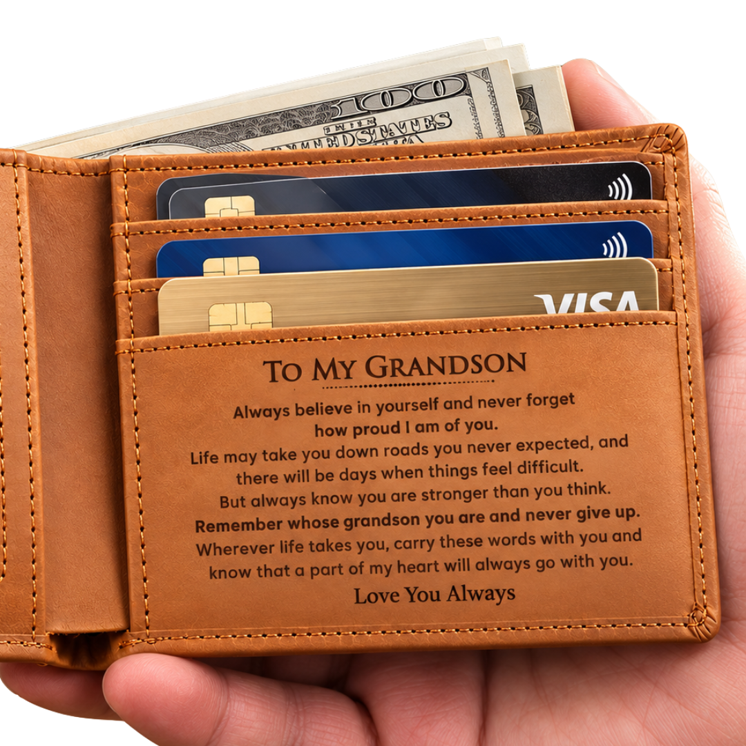 A tan leather bifold wallet held in a hand, showing card slots filled with credit cards and cash, plus an engraved message on the inside addressed to a grandson.