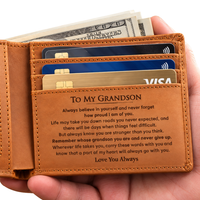 Thumbnail for A tan leather bifold wallet held in a hand, showing card slots filled with credit cards and cash, plus an engraved message on the inside addressed to a grandson.