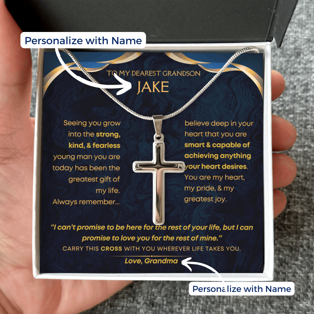 Silver cross necklace in a box with personalized message to a grandson, held by a hand.