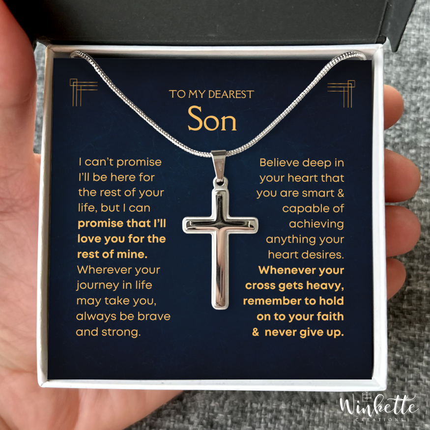 Silver cross necklace in a box with a message for a son, held by a hand from mom dad
