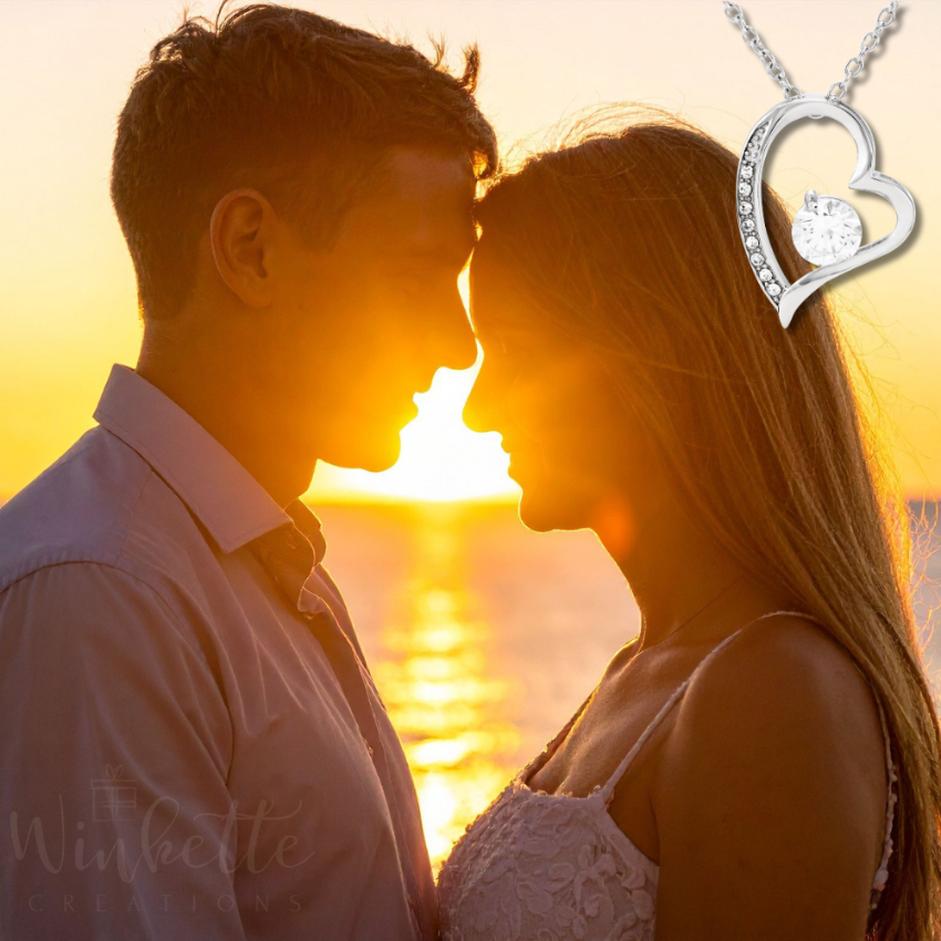 Romantic husband and wife at sunset by the ocean with forever love heart necklace, meaningful gift for wife from husband
