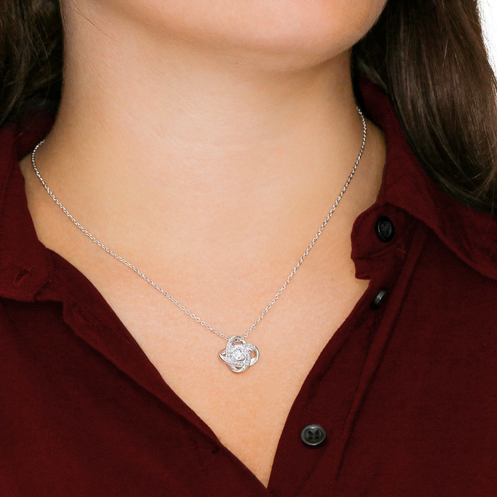 Woman wearing silver love knot pendant necklace with cubic zirconia crystal – granddaughter gift jewelry.