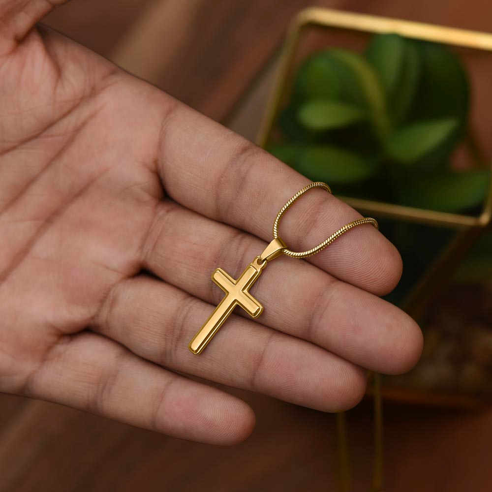 Gold Cross necklace held by hand. 