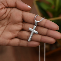 Thumbnail for Silver cross pendant on a chain held in a hand with a blurred background