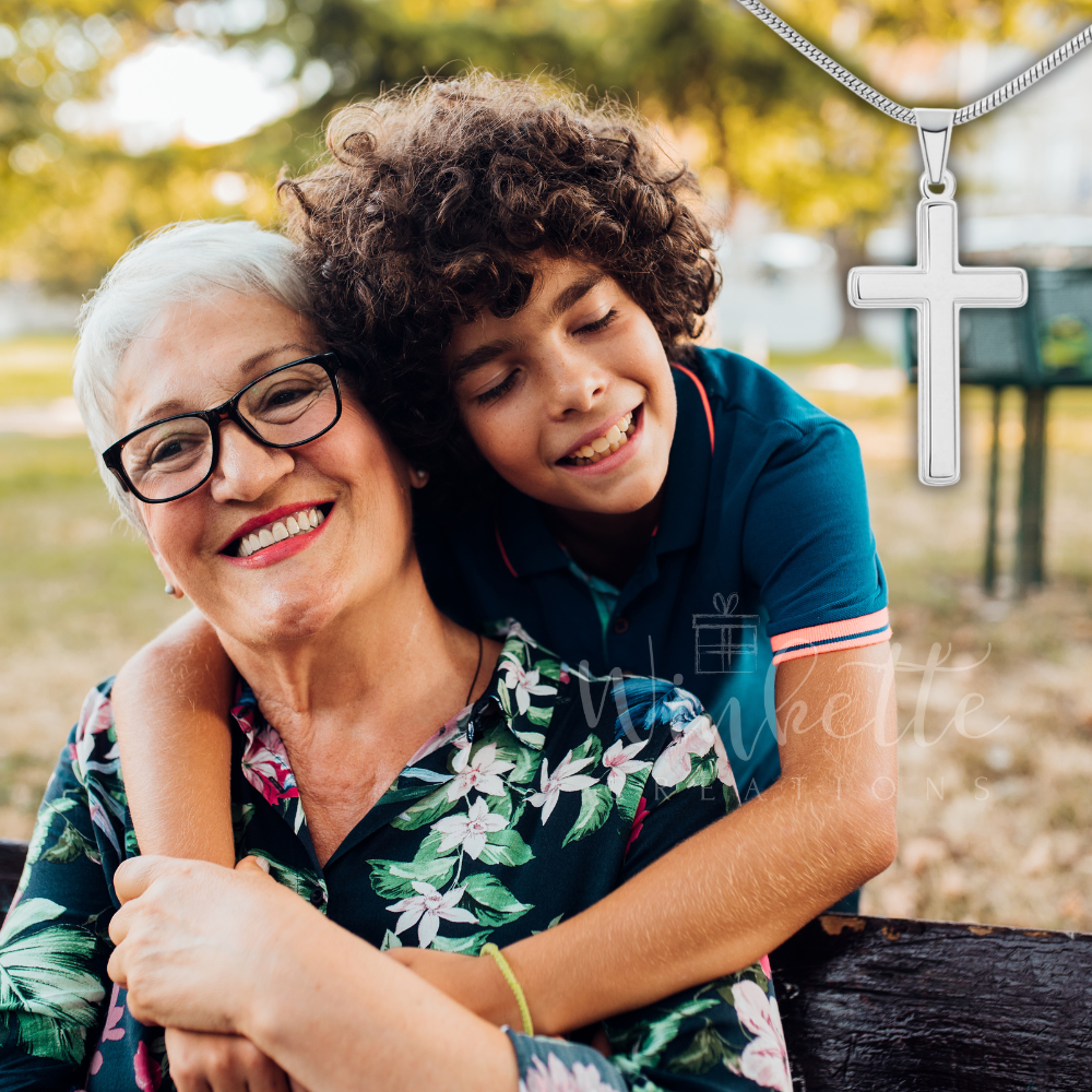 Grandma with glasses and a grandson embracing outdoors, with a cross necklace displayed.