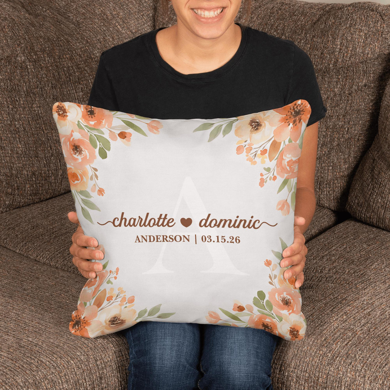 Person holding a decorative pillow with floral design and personalized text.