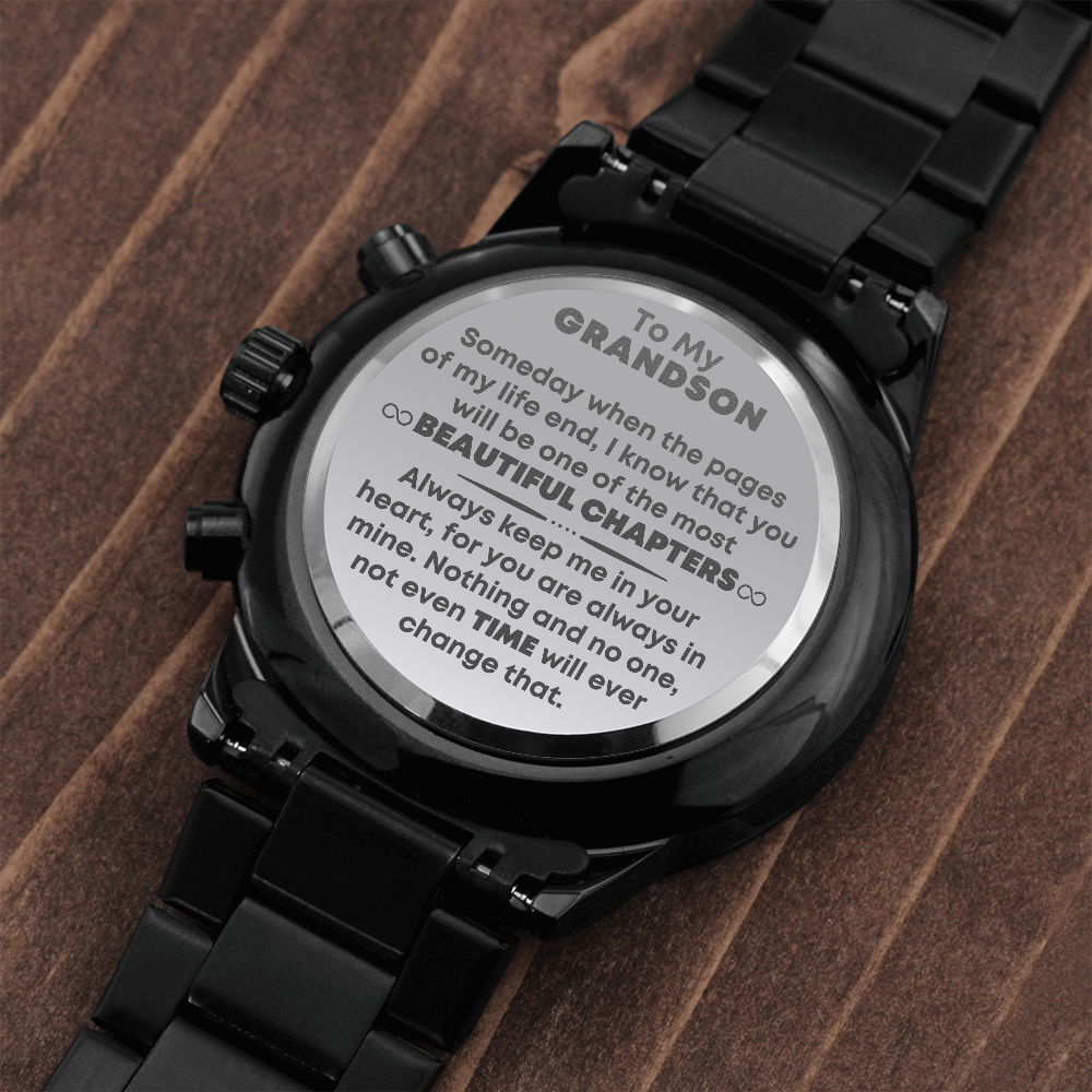 A black chronograph grandson engraved wristwatch with an engraved heartfelt message for grandson, displayed on a wooden surface. It has a link bracelet and a chronograph function with three dials on the face.